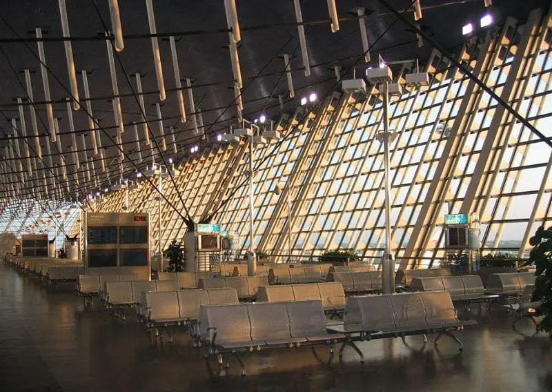 大型機場候機區與航廈窗景,轉機需預留安檢與步行時間