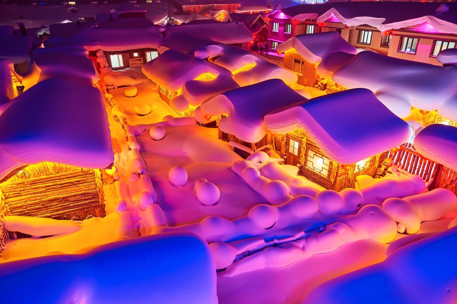 雪鄉木屋覆蓋厚雪,夜間燈光映照雪蘑菇屋頂