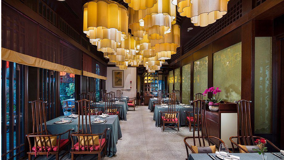 杭州西溪悅榕莊白雲中餐廳的長條用餐區、雲朵造型燈罩吊燈與紅木圈椅