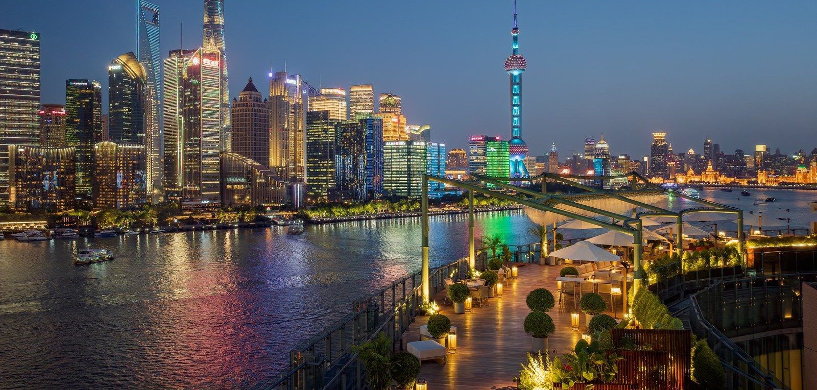 從上海外灘悅榕莊高處看出去的黃浦江夜景，左側是對岸的陸家嘴高樓與東方明珠，右前方是館內亮燈的露台
