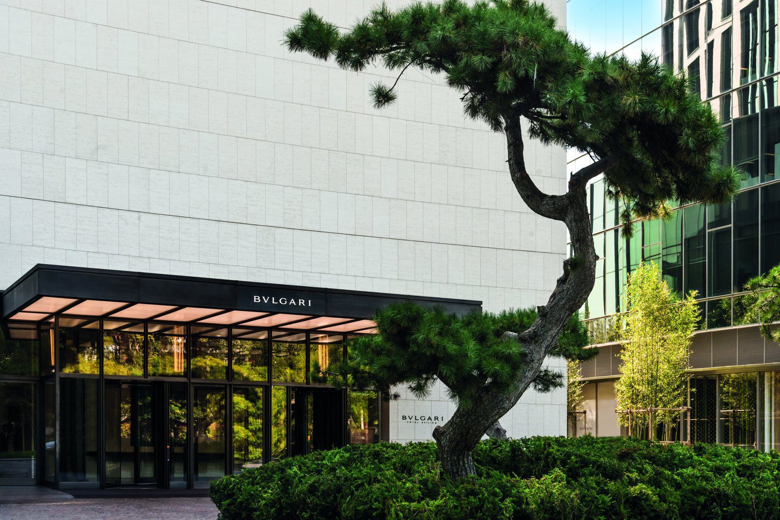北京寶格麗酒店的石材立面入口、BVLGARI 字樣雨遮與松樹