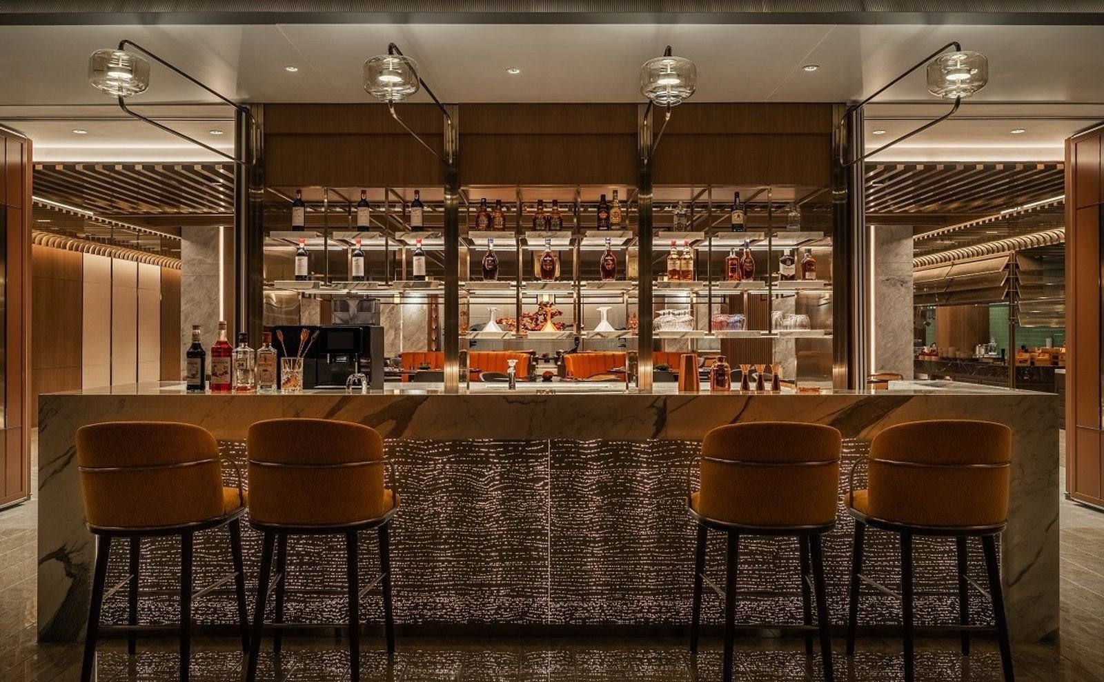 西安曲江希爾頓嘉悅里酒店 TIPSY 微醺吧，大理石吧檯前是四張橘色高腳椅，後方酒架擺滿酒瓶