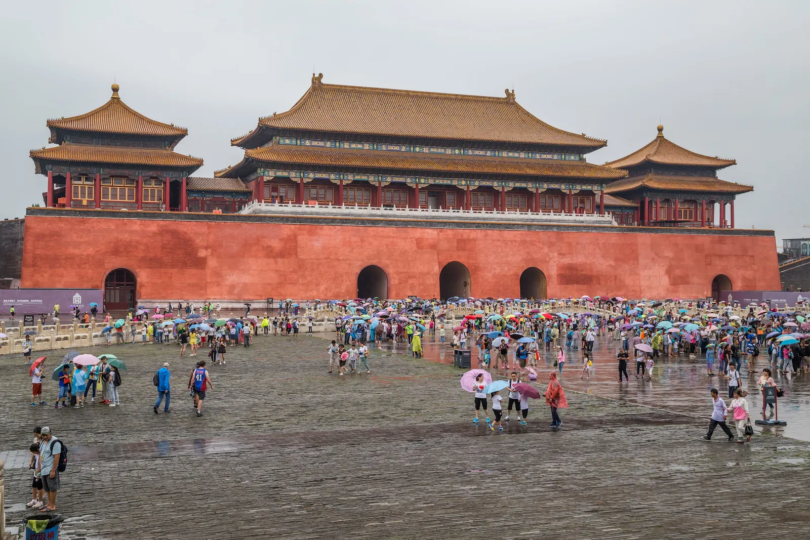 旅客撐傘穿越濕潤的戶外廣場