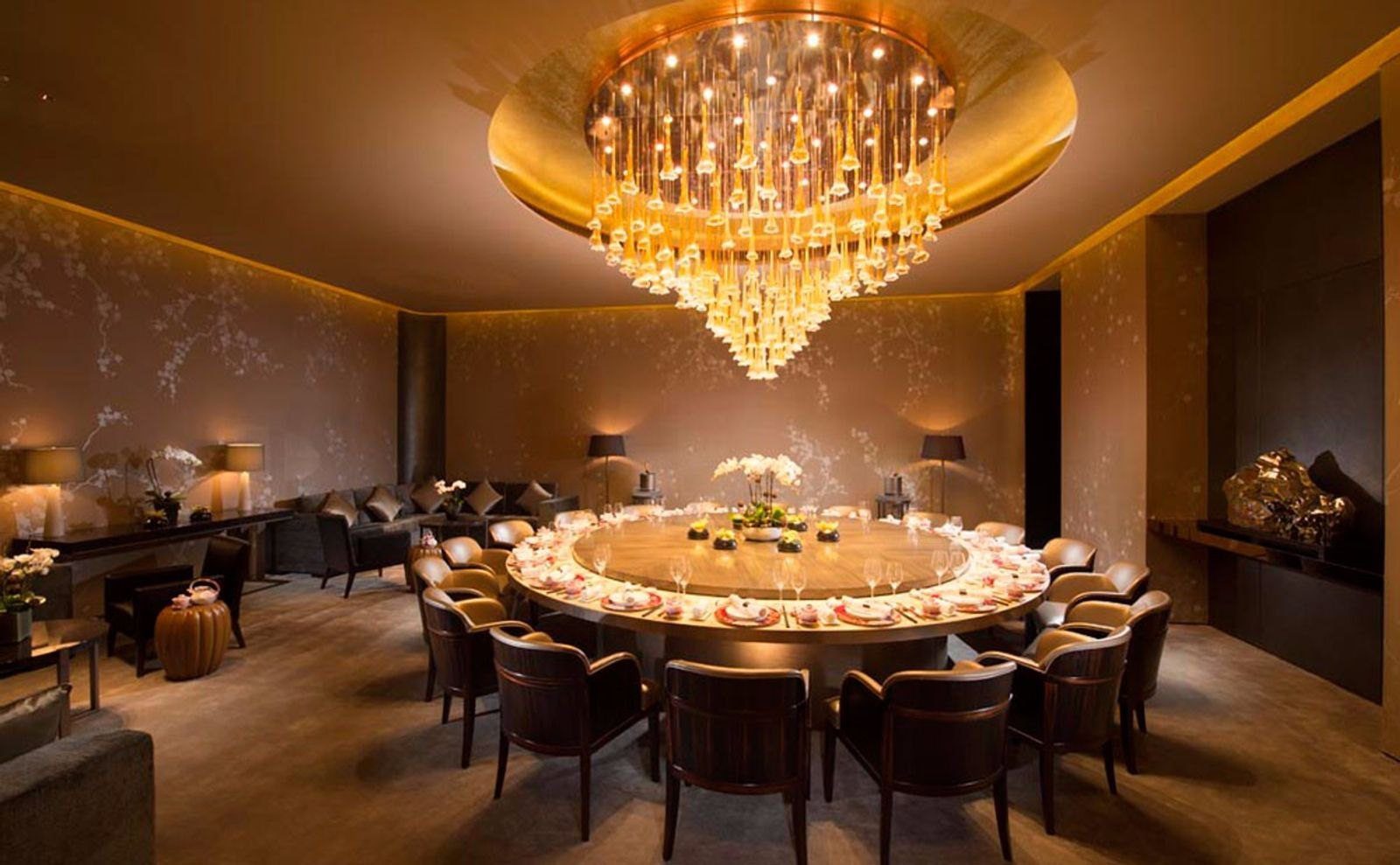 北京康萊德酒店陸羽的私人包房，大圓桌已擺好餐具，上方垂掛金色吊燈，牆面是花枝圖案