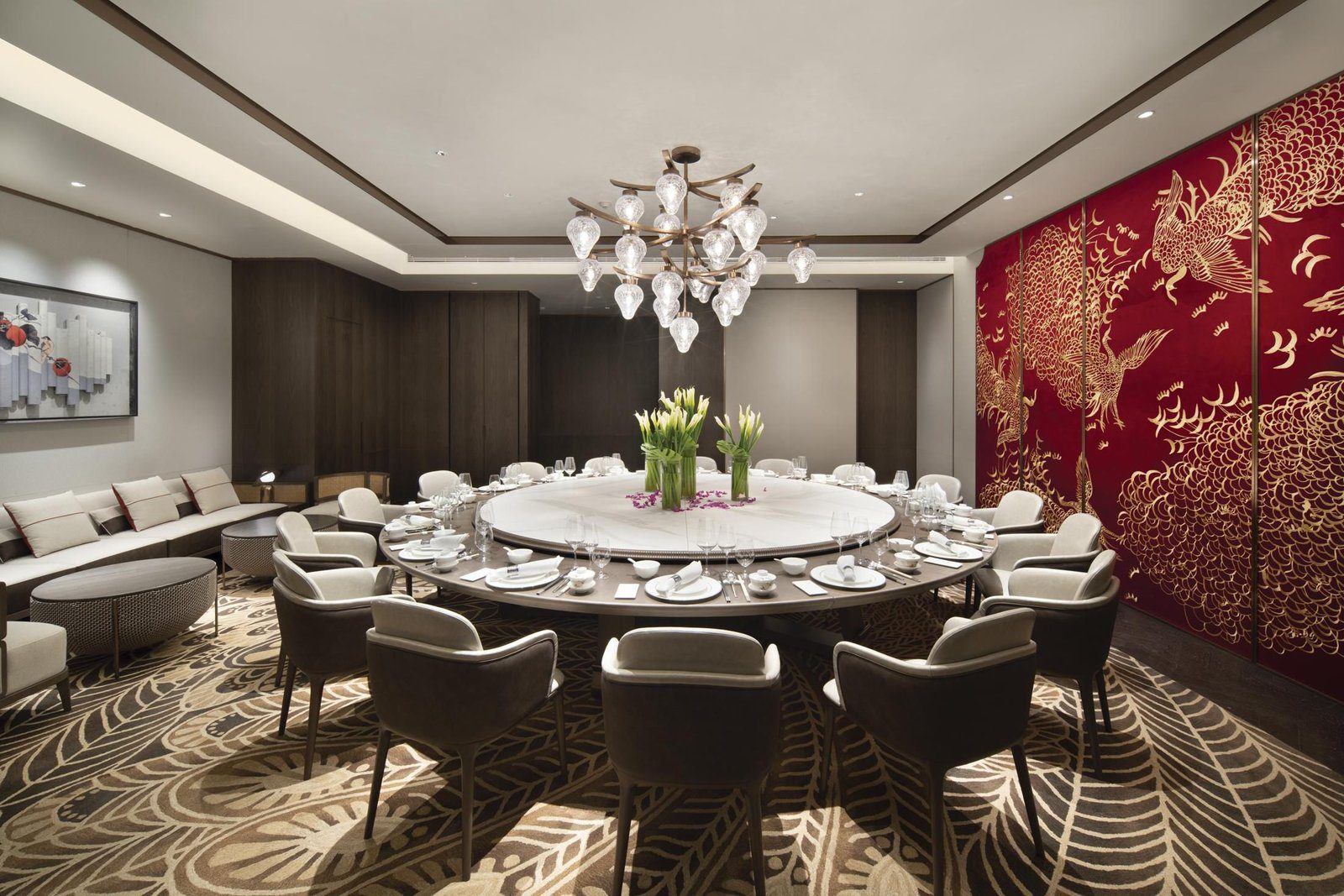 北京金隅八達嶺皇冠假日酒店彩豐小館鳳凰包廂，水晶吊燈下的大圓桌擺好餐具與白色花束，右側整面紅底金色鳳鳥壁畫