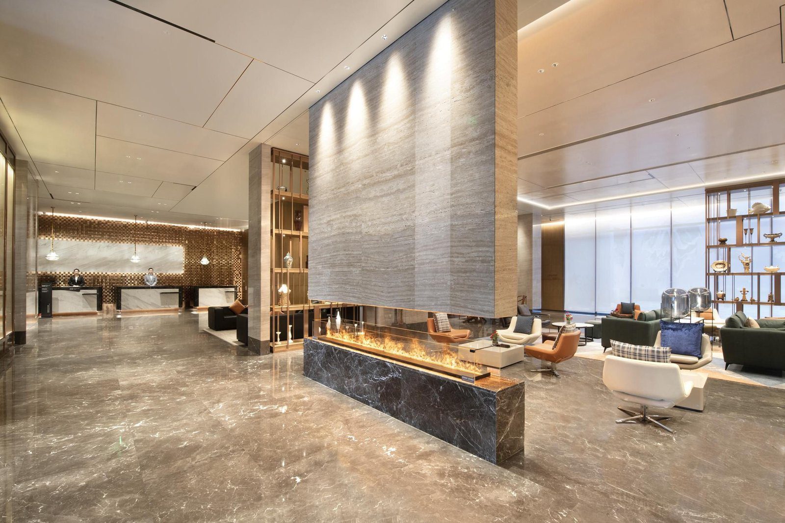 大連星海皇冠假日酒店大堂,石材牆下方是一整排火爐,右側是沙發座位區,左後方是接待櫃檯