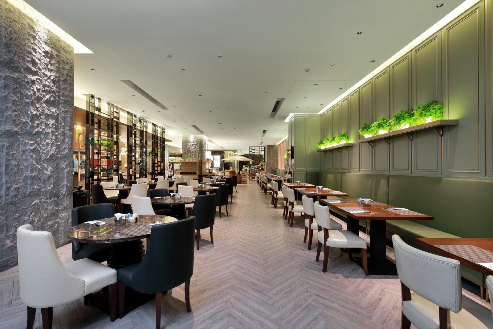 南京銀城皇冠假日酒店 L-cafe 自助餐廳，人字拼地板兩側是綠色牆板卡座與石材柱，深處是餐檯區