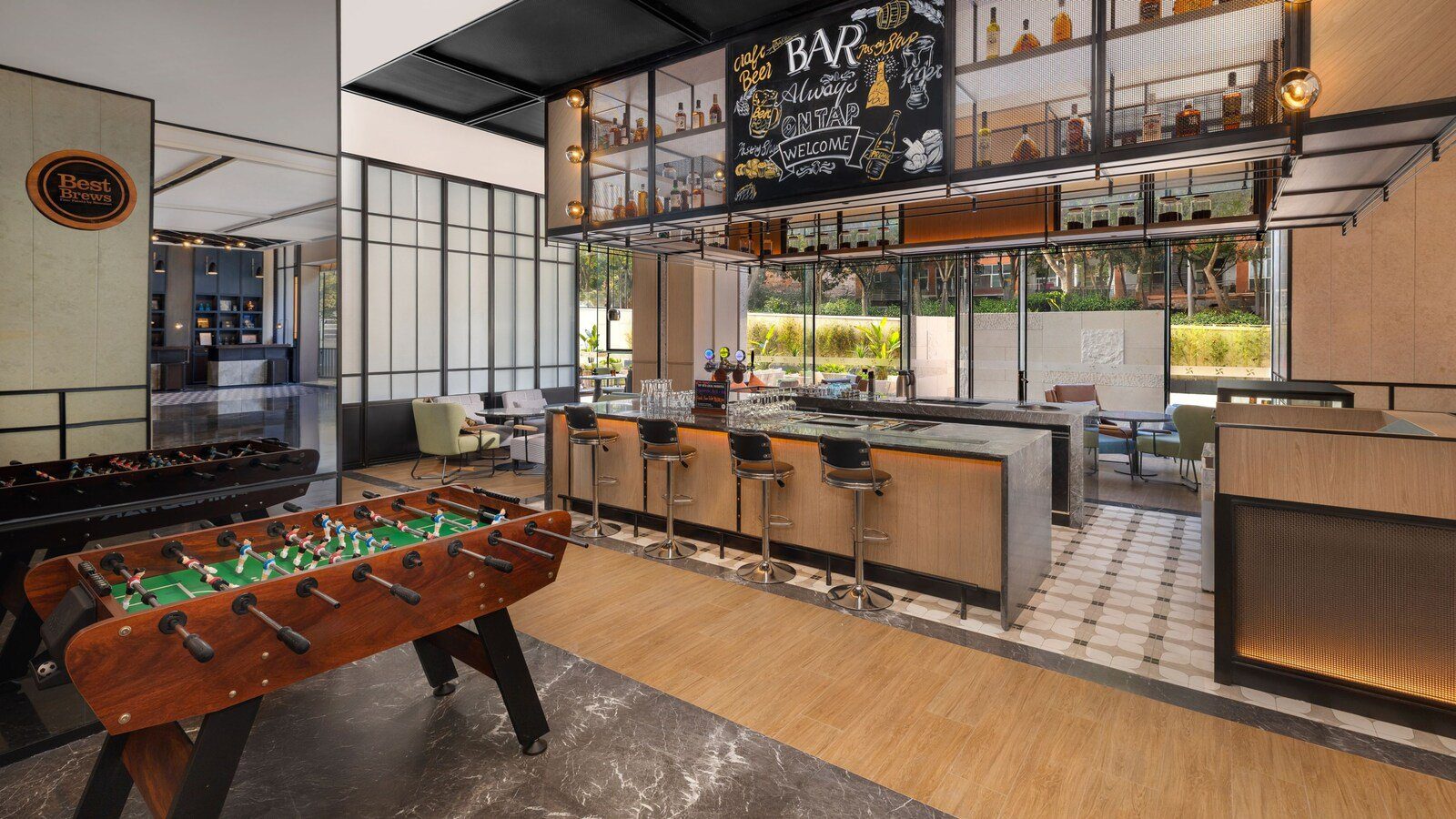 成都東站福朋喜來登酒店的大堂吧，黑板上寫著 BAR 字樣，吧檯前排著高腳椅，左側是手足球台