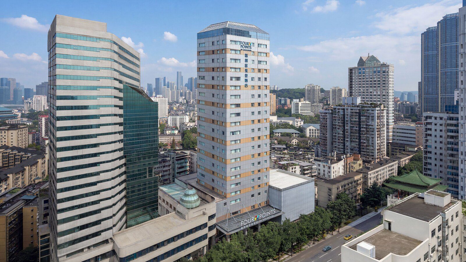 重慶渝中半島福朋喜來登酒店白天外觀，塔樓前是掛著 FOUR POINTS 招牌的入口雨遮與行道樹，右側是綠色琉璃瓦的傳統屋頂