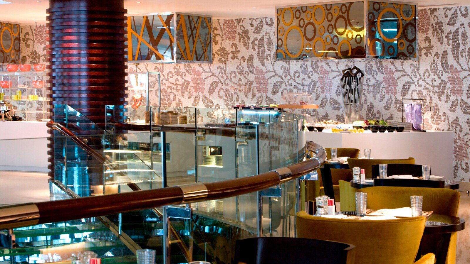 杭州龍禧福朋喜來登酒店全日餐廳的自助檯與座位，牆面是花卉圖案的馬賽克，前方是玻璃扶手的樓梯