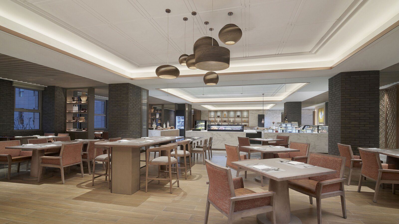 蘇州吳中福朋喜來登酒店的 The Eatery 全日餐廳，灰磚柱之間排著木桌與磚紅色椅子，後方是自助檯