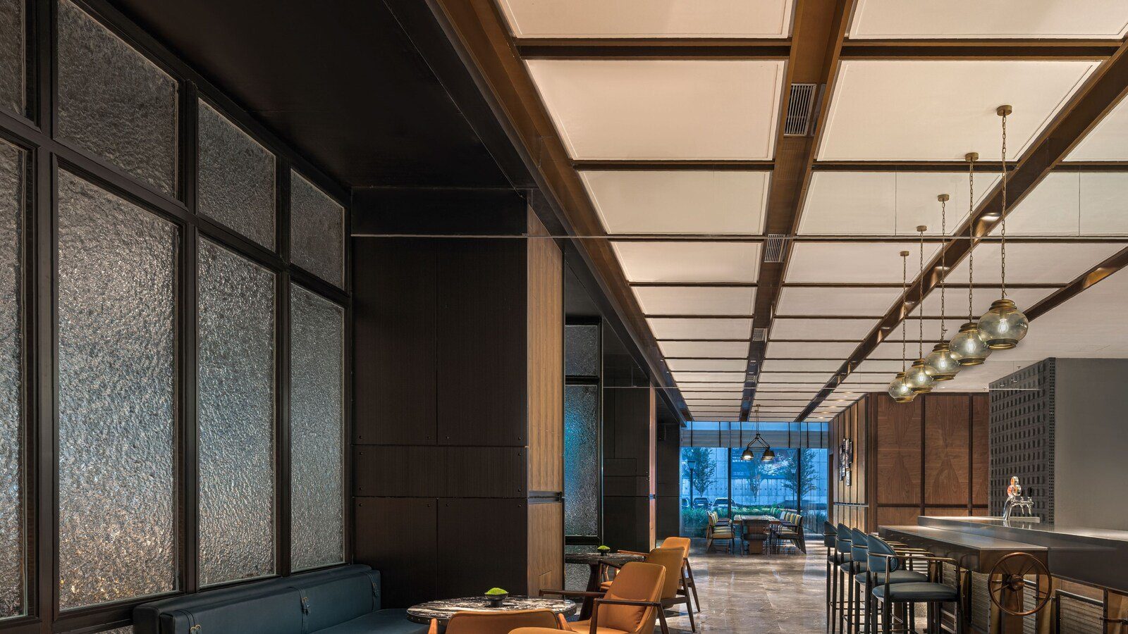 烏魯木齊中建福朋喜來登酒店 The Mesh 酒吧，右側是金屬吧台與一排高腳椅，上方垂著綠色玻璃吊燈，左側是藍色卡座與橘色扶手椅