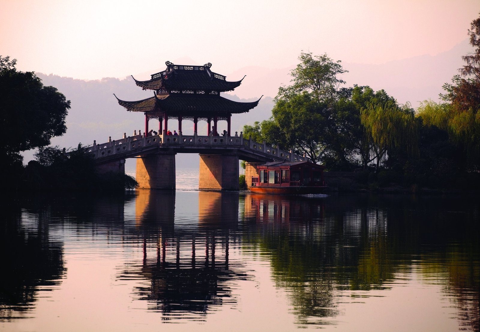西湖湖面的重簷亭橋與一艘木船在夕照中的倒影(酒店周邊景點)