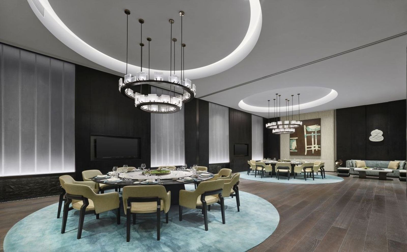 南京牛首山希爾頓酒店青雅中餐廳的用餐區，兩張大圓桌擺在藍綠色圓形地毯上，上方垂下環形吊燈，角落有沙發區