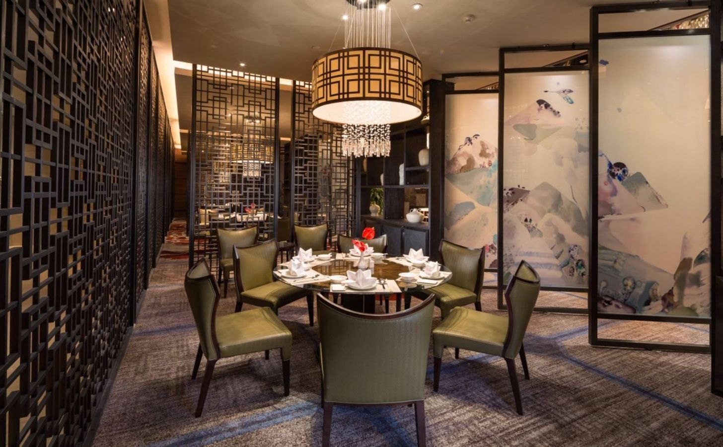 烏魯木齊希爾頓酒店御璽中餐廳，深色木格屏風圍出用餐區，圓桌配綠色皮椅，右側是水彩山景屏風，上方垂著方格燈罩吊燈