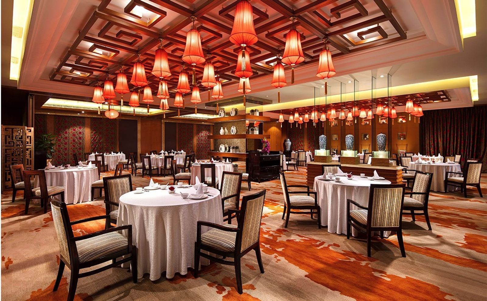 廈門磐基希爾頓酒店悅園中餐廳，格柵天花板垂掛整片紅色燈籠，下方是鋪白桌布的圓桌
