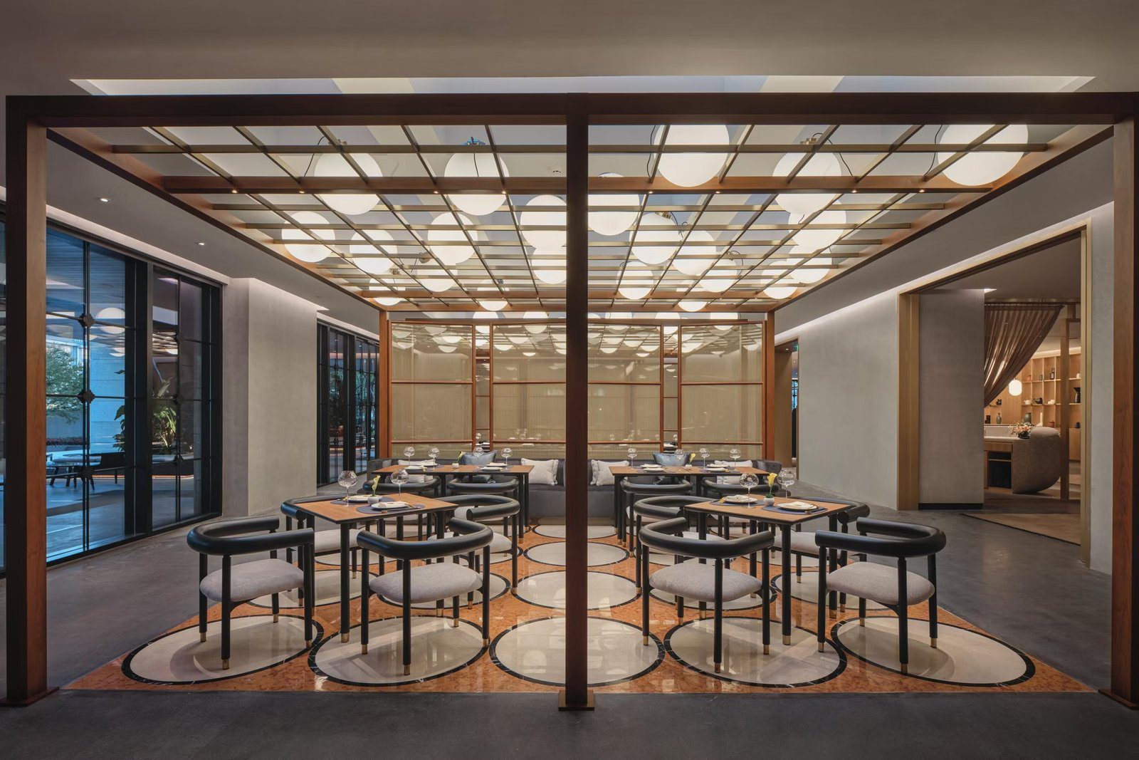 杭州上城英迪格酒店餐廳用餐區的方桌座位、圓弧扶手椅與整片球形燈組成的格柵天花