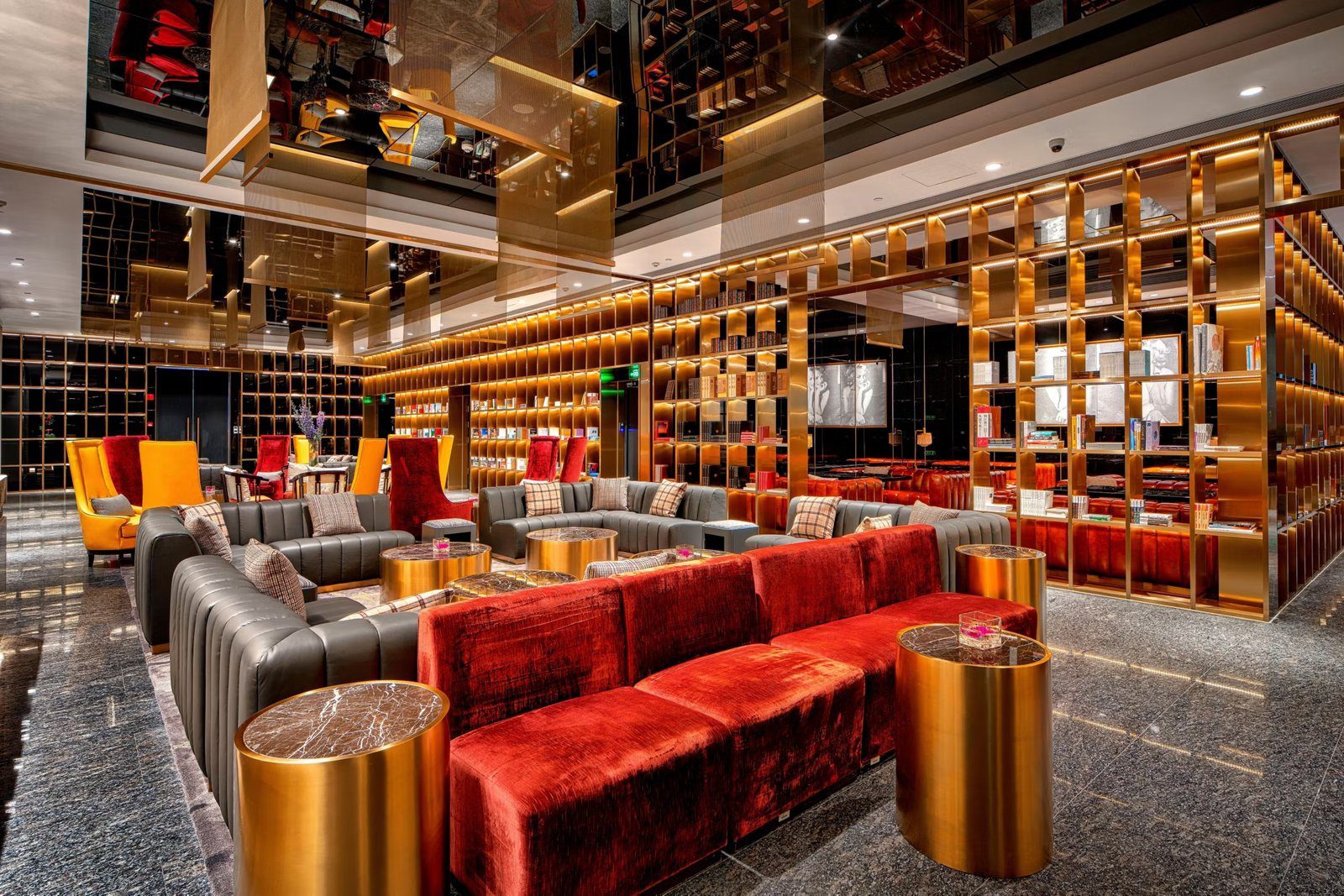 上海靜安英迪格酒店休憩區的金色格狀酒櫃牆、紅色絨布沙發與圓形金屬邊桌