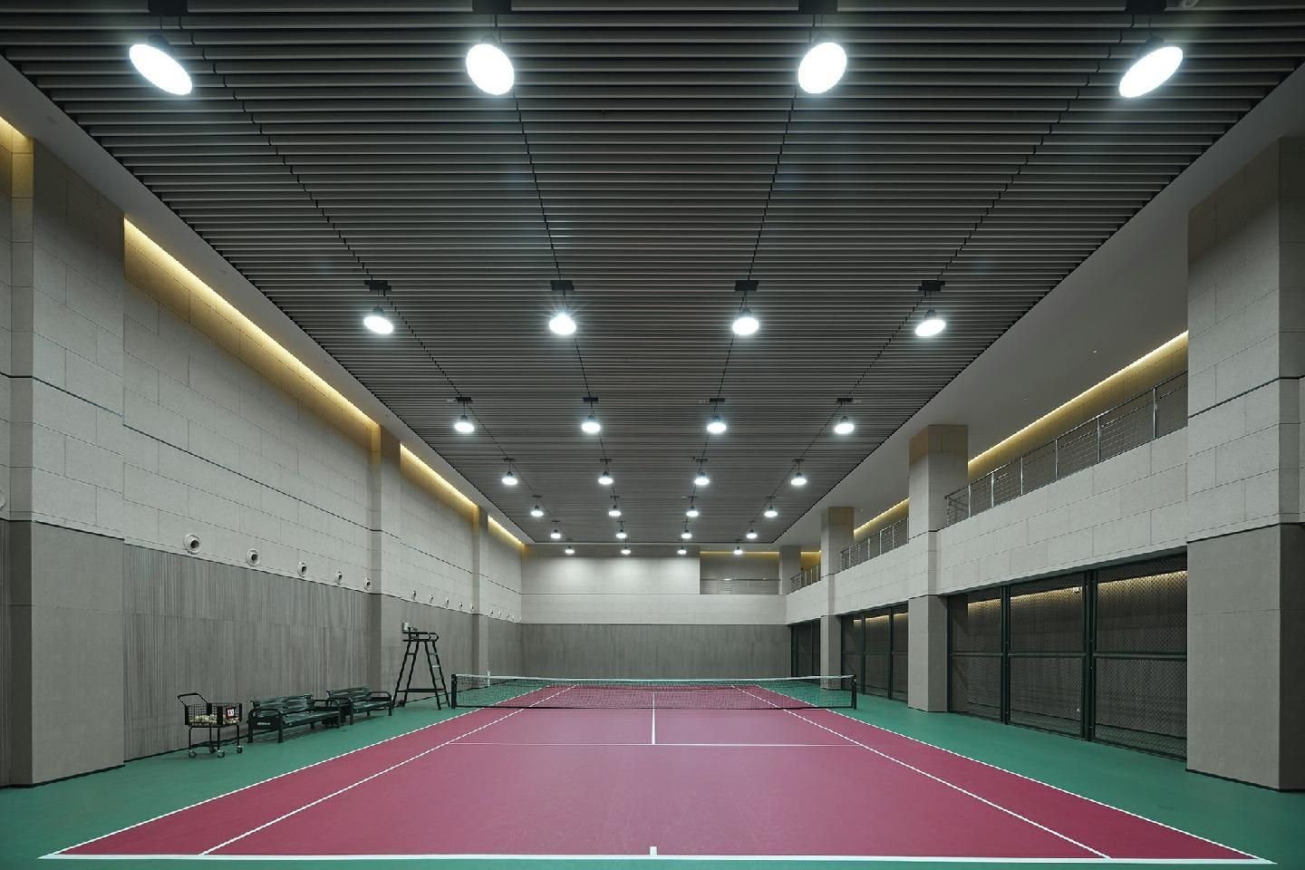 南京長江之舟華邑酒店康體中心室內網球場，紅綠色硬地球場上方掛著一排照明燈，場邊有裁判椅與長椅