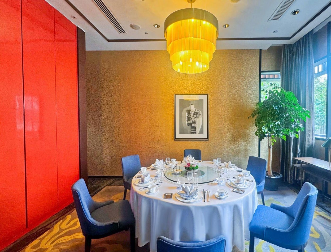上海衡山路十二號華邑酒店中餐包廂，金色層疊吊燈下是鋪白桌布的圓桌與藍色餐椅，左側是整面紅色牆板