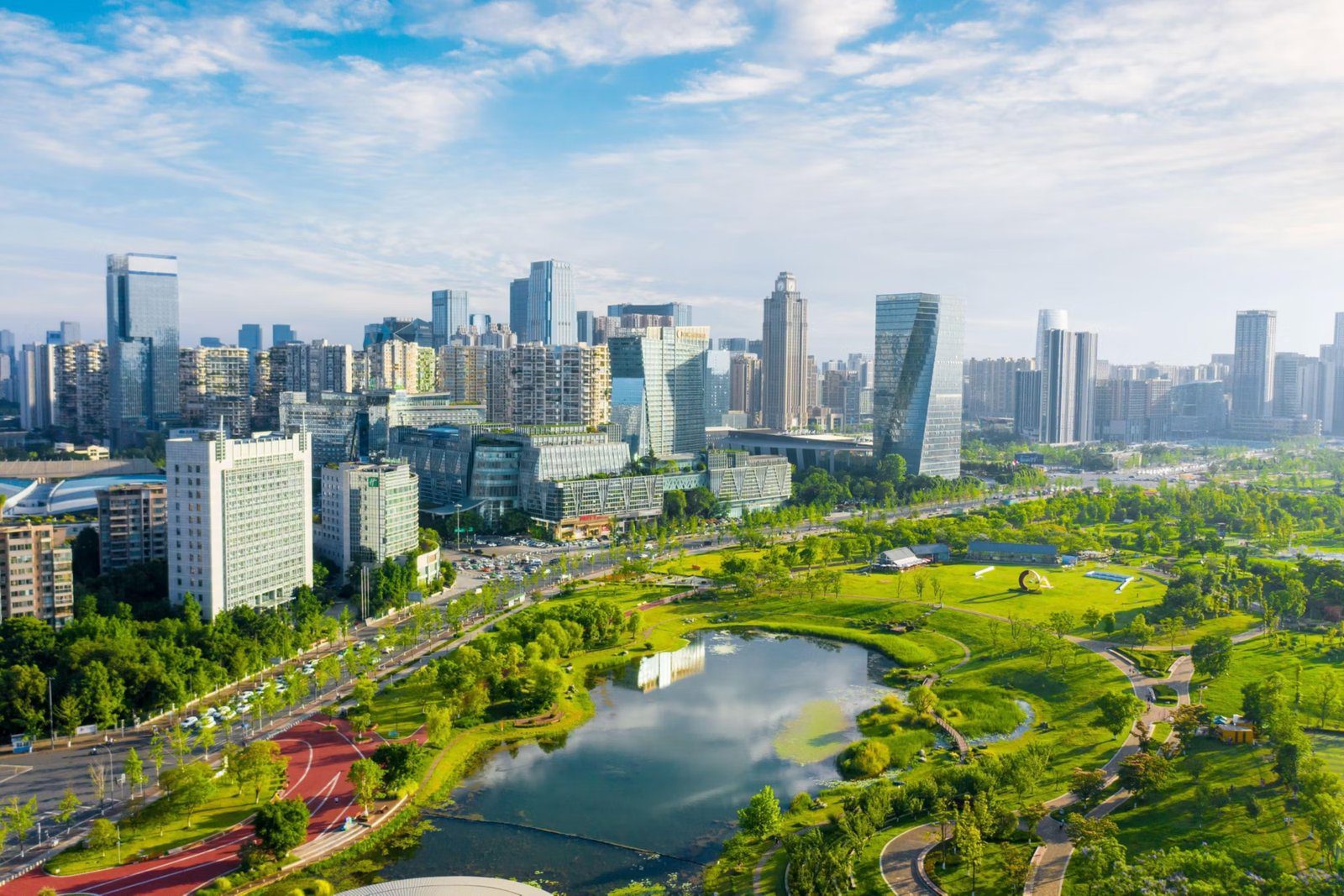 自高處俯瞰成都高新區的城市天際線與大片綠地公園,中央有湖面、環形步道與紅色跑道,是飯店周邊的桂溪公園一帶景色