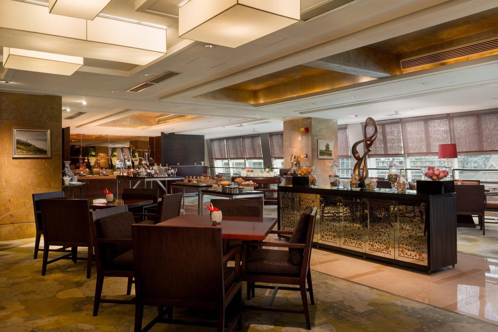 成都世紀城天堂洲際大飯店行政樓層酒廊的木質餐桌與深色扶手椅，右側是鏡面櫃與水果點心陳列檯，窗邊拉著百葉簾