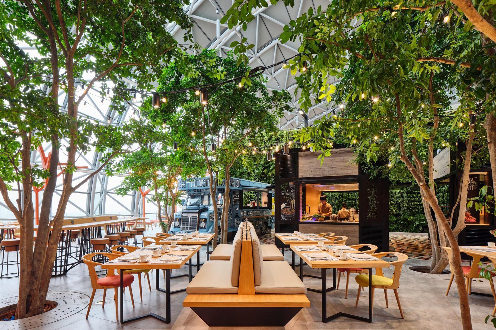 重慶來福士洲際酒店 Botanica 餐廳玻璃拱頂下的樹木、餐車與座位