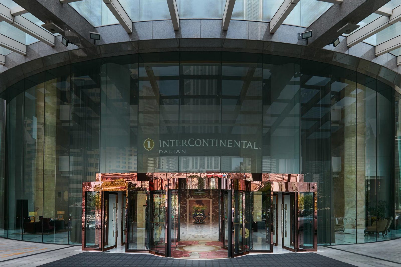 大連中遠海運洲際酒店正門，玻璃帷幕上有 InterContinental Dalian 字樣，下方是玫瑰金色的旋轉門