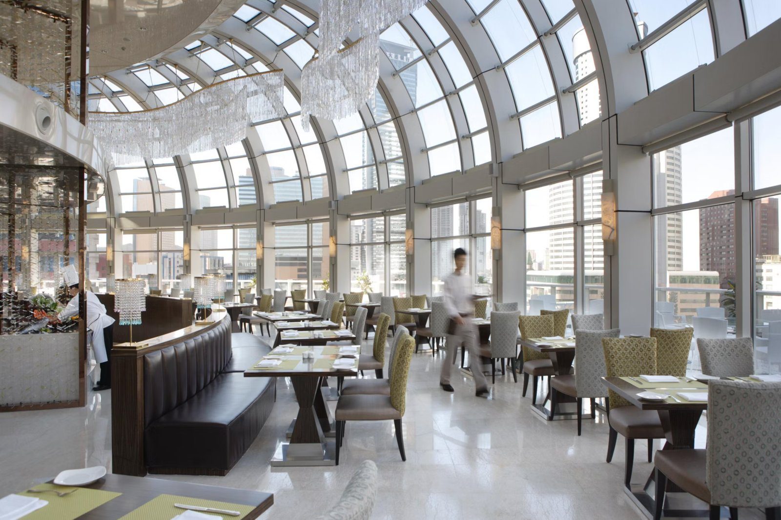 大連中遠海運洲際酒店的餐廳，弧形玻璃屋頂與落地窗環繞用餐區，窗外是市區高樓