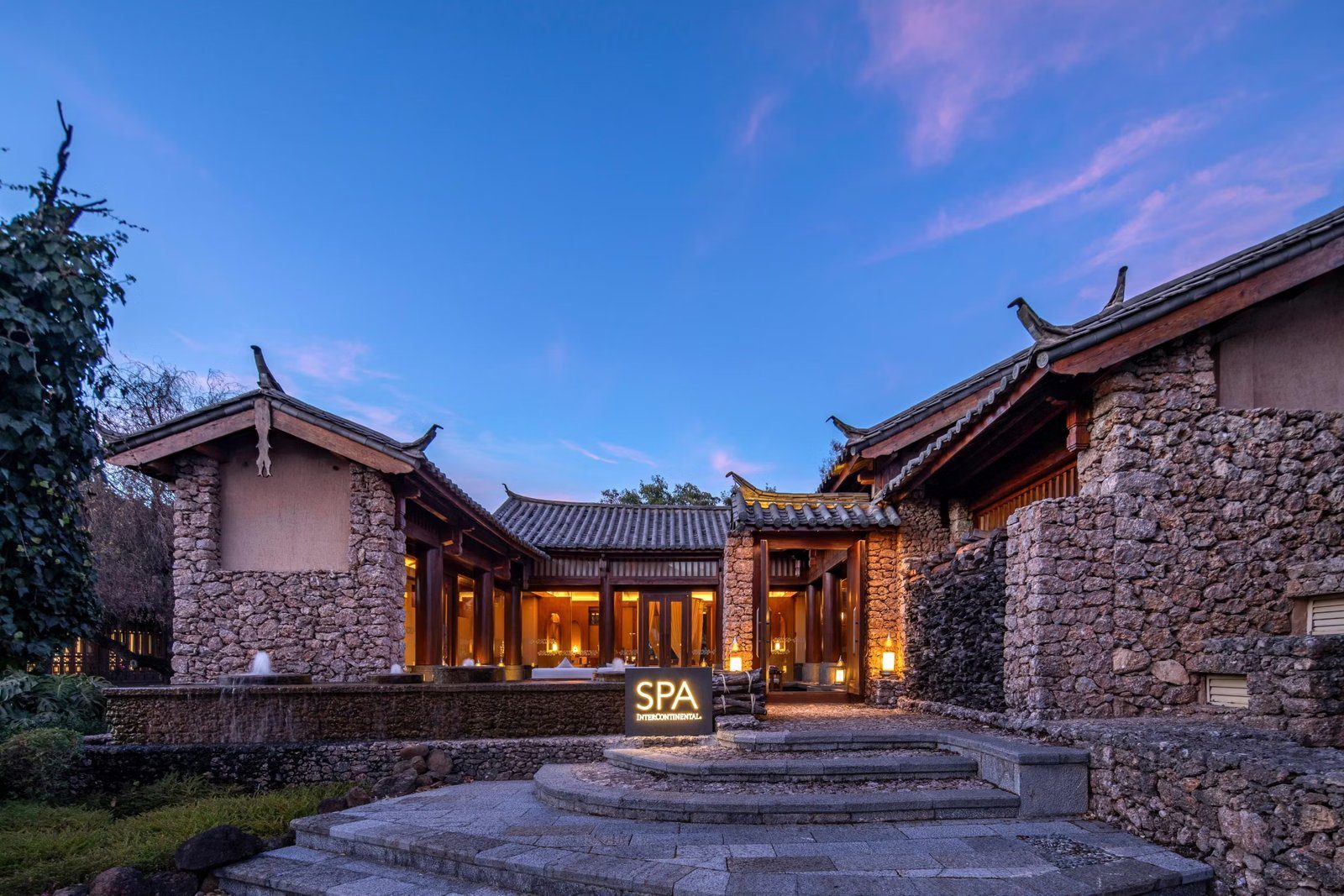 暮色中的石砌院落建築亮著暖燈，弧形石階前立著 SPA InterContinental 燈箱招牌