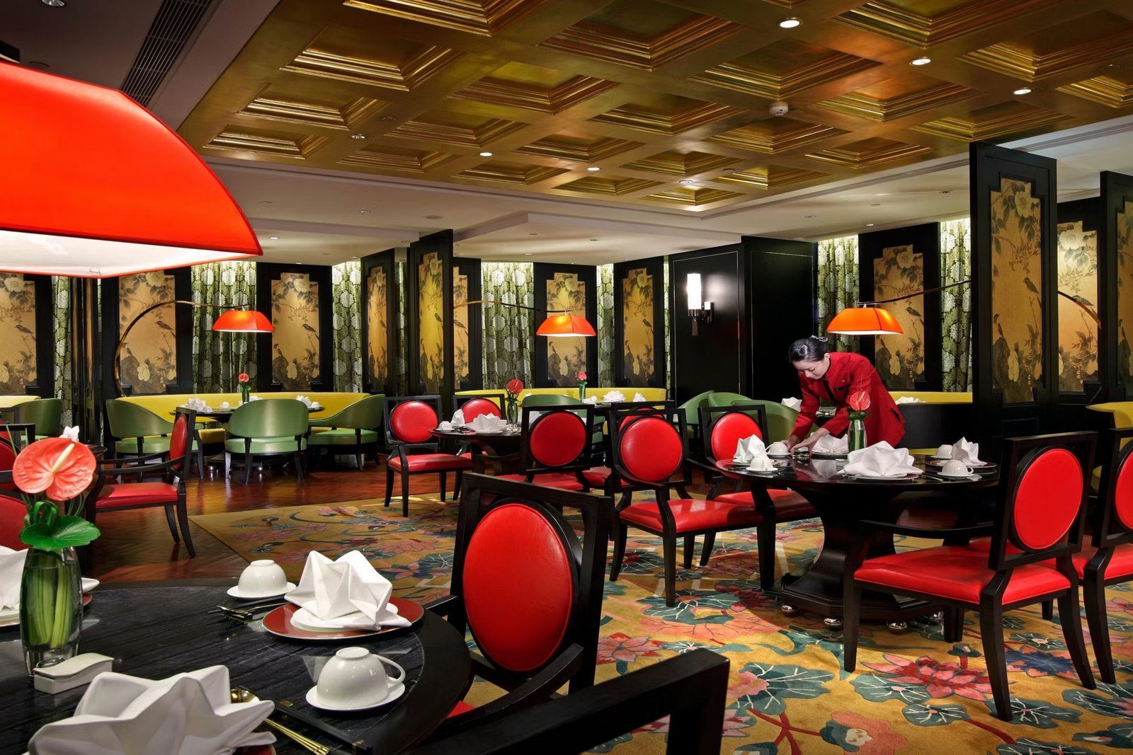 上海靜安洲際酒店中餐廳用餐區的金色格狀天花、紅色圓背座椅與花鳥屏風