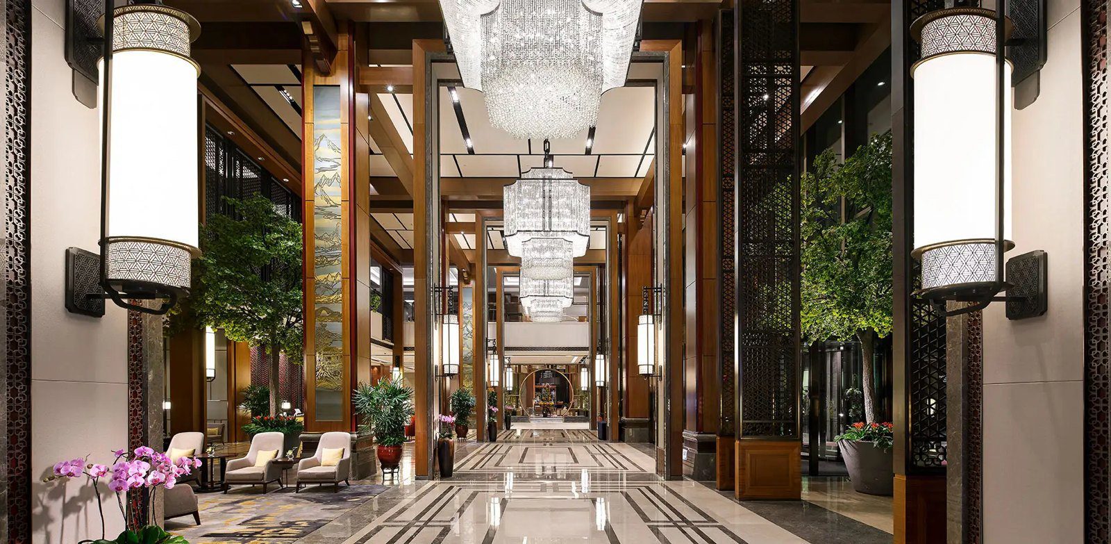 濟南香格里拉大酒店大堂，兩側立著大型燈柱，中央一路垂掛水晶吊燈，地面是拼花石材