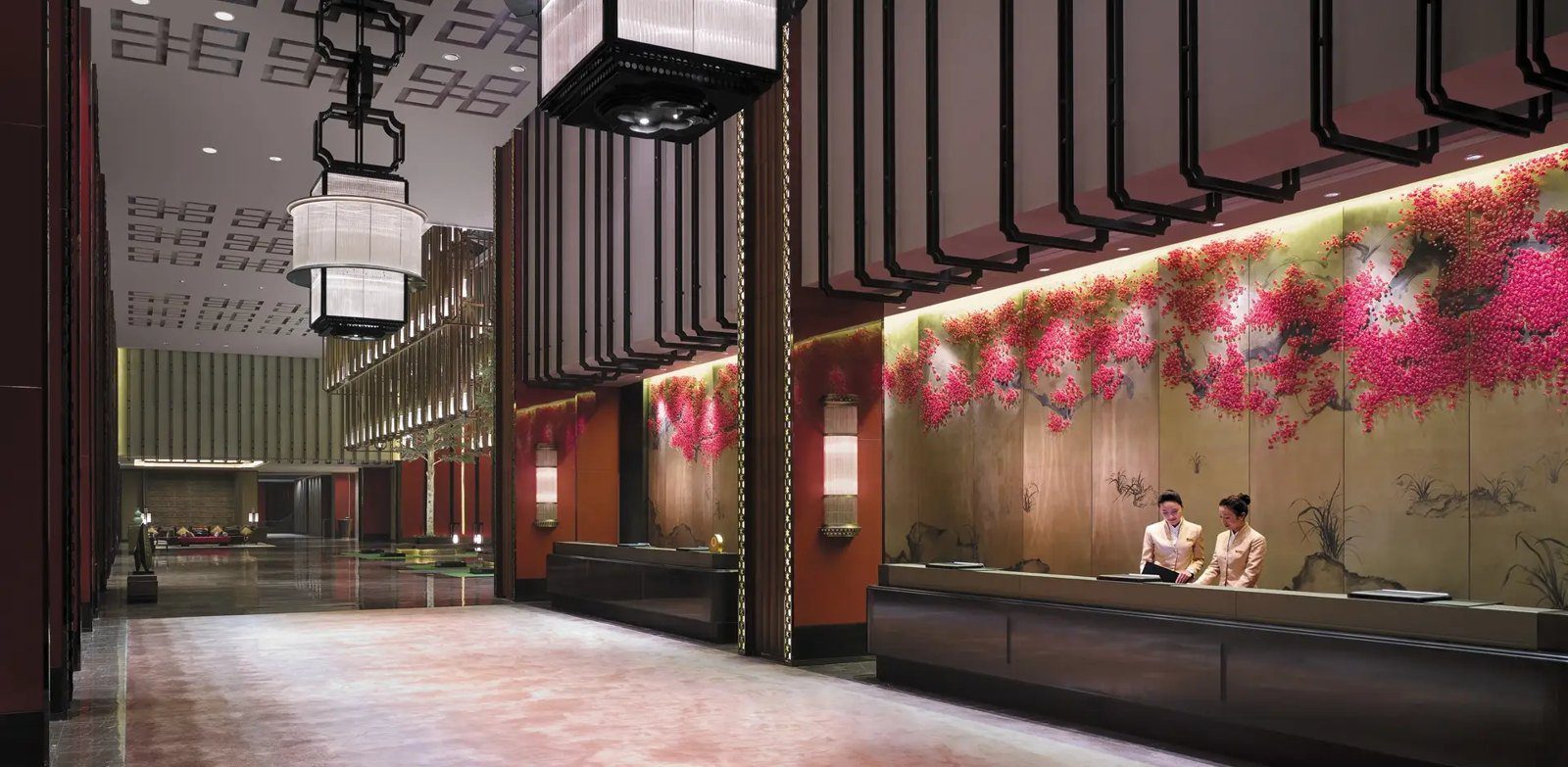 曲阜香格里拉大酒店接待櫃台，後方整面牆繪著紅色花樹，天花板垂掛方形宮燈