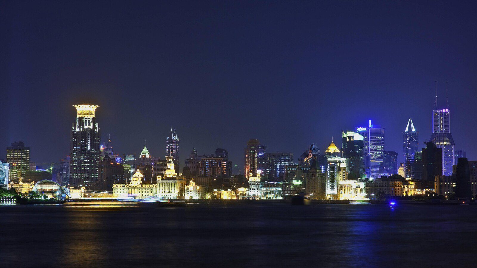 黃浦江對岸的外灘歷史建築群夜景，江面倒映兩岸燈光