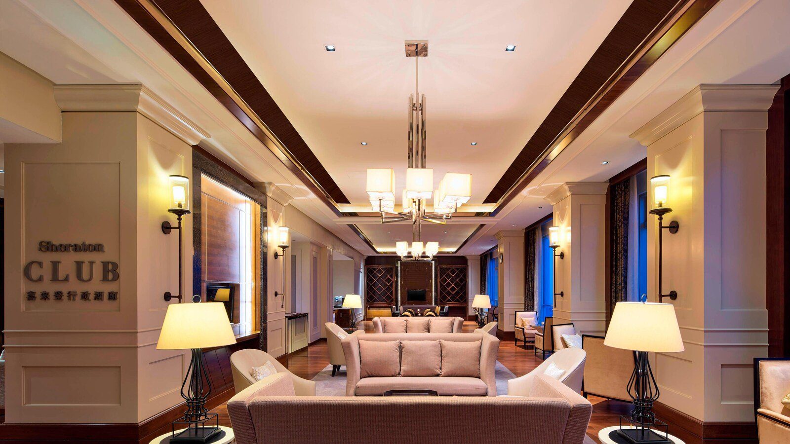 青島膠州綠城喜來登酒店 Sheraton Club 酒廊，柱上掛著 Sheraton CLUB 字樣，中間是成排沙發與吊燈