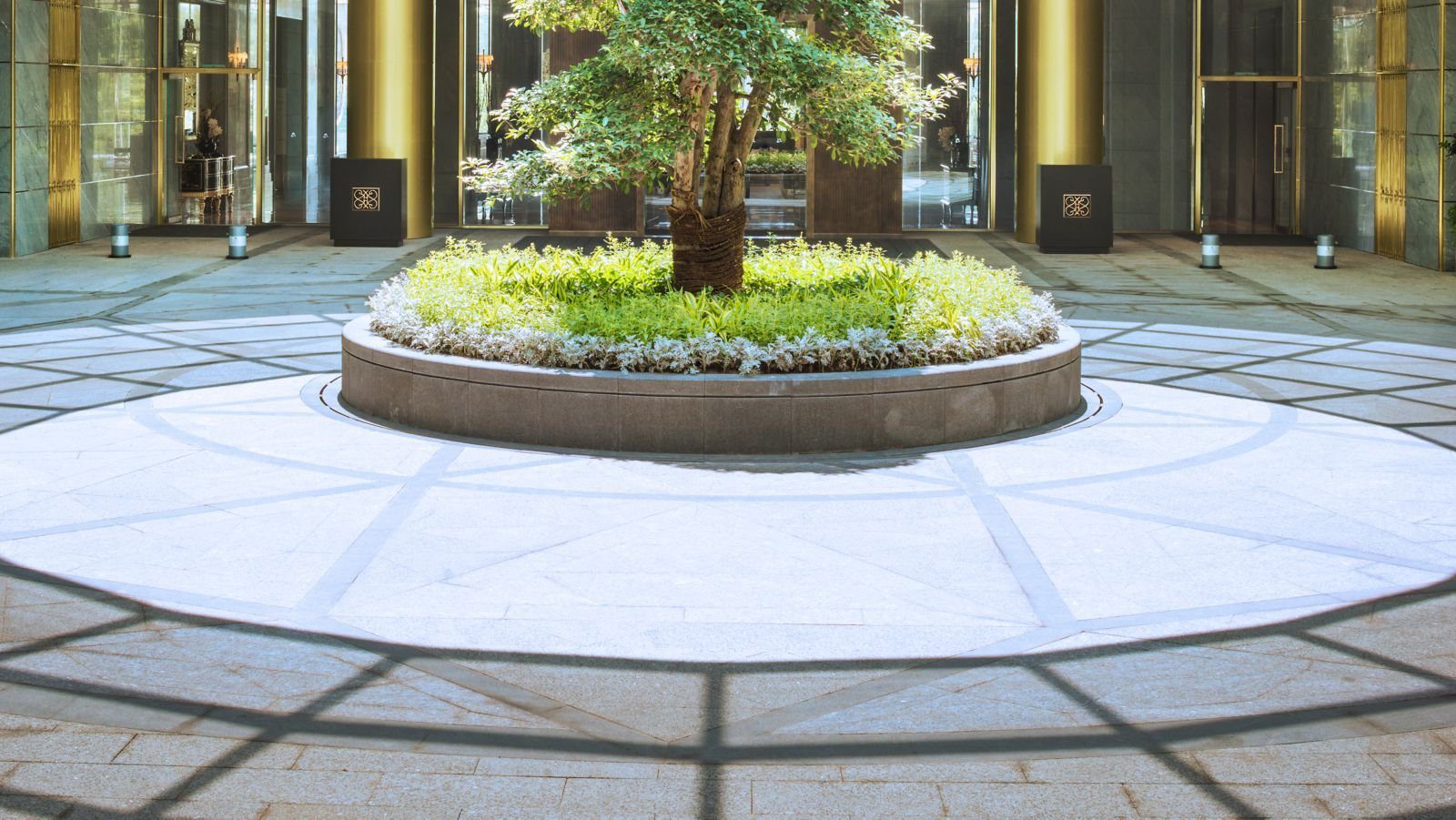 杭州綠城尊藍錢江豪華精選酒店入口門廳的圓形植栽花圃、金色柱列與石材地坪