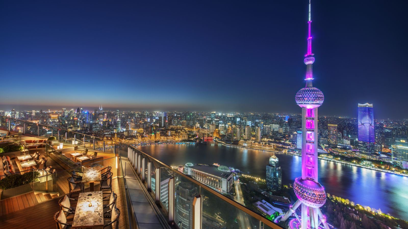 上海浦東麗思卡爾頓酒店 FLAIR 頂樓露台的木地板座位區，正對點燈的東方明珠與外灘夜景