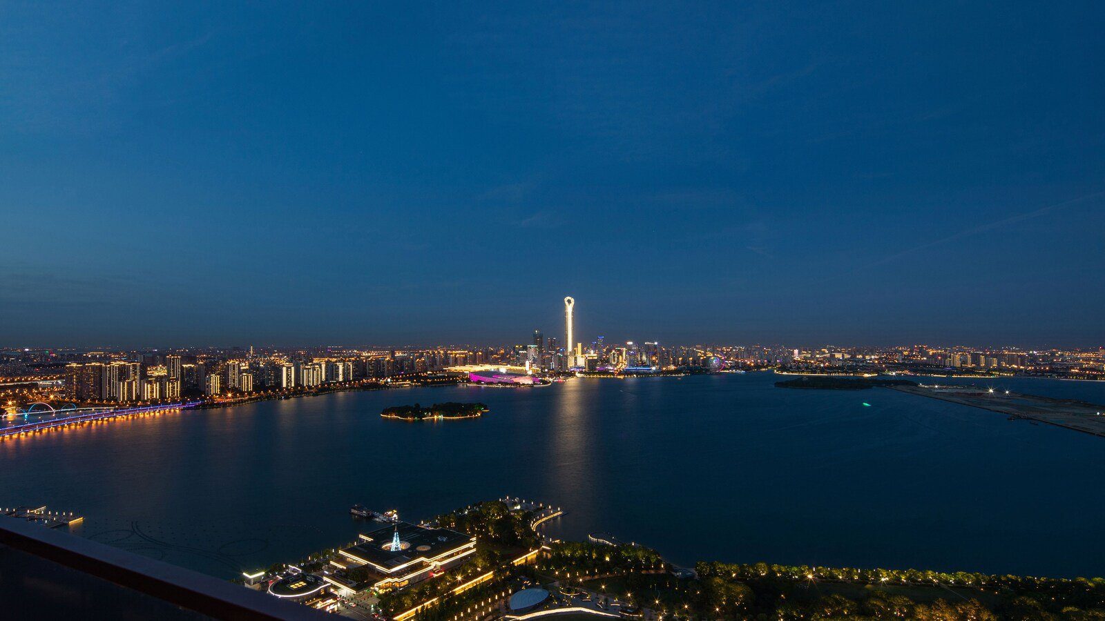 自蘇州 W 酒店高處俯瞰的夜間湖景:湖面、湖心小島與對岸的城市燈火,遠處有一座照明高塔