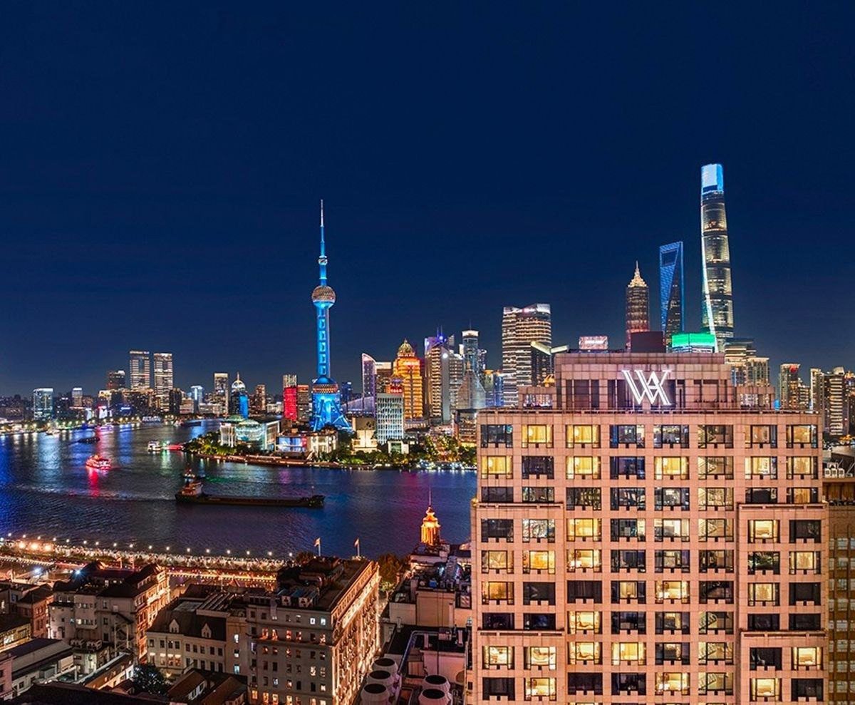 夜晚從高處看黃浦江兩岸,右側是上海外灘華爾道夫酒店新翼大樓頂的 WA 標誌,江對岸是東方明珠與陸家嘴高樓
