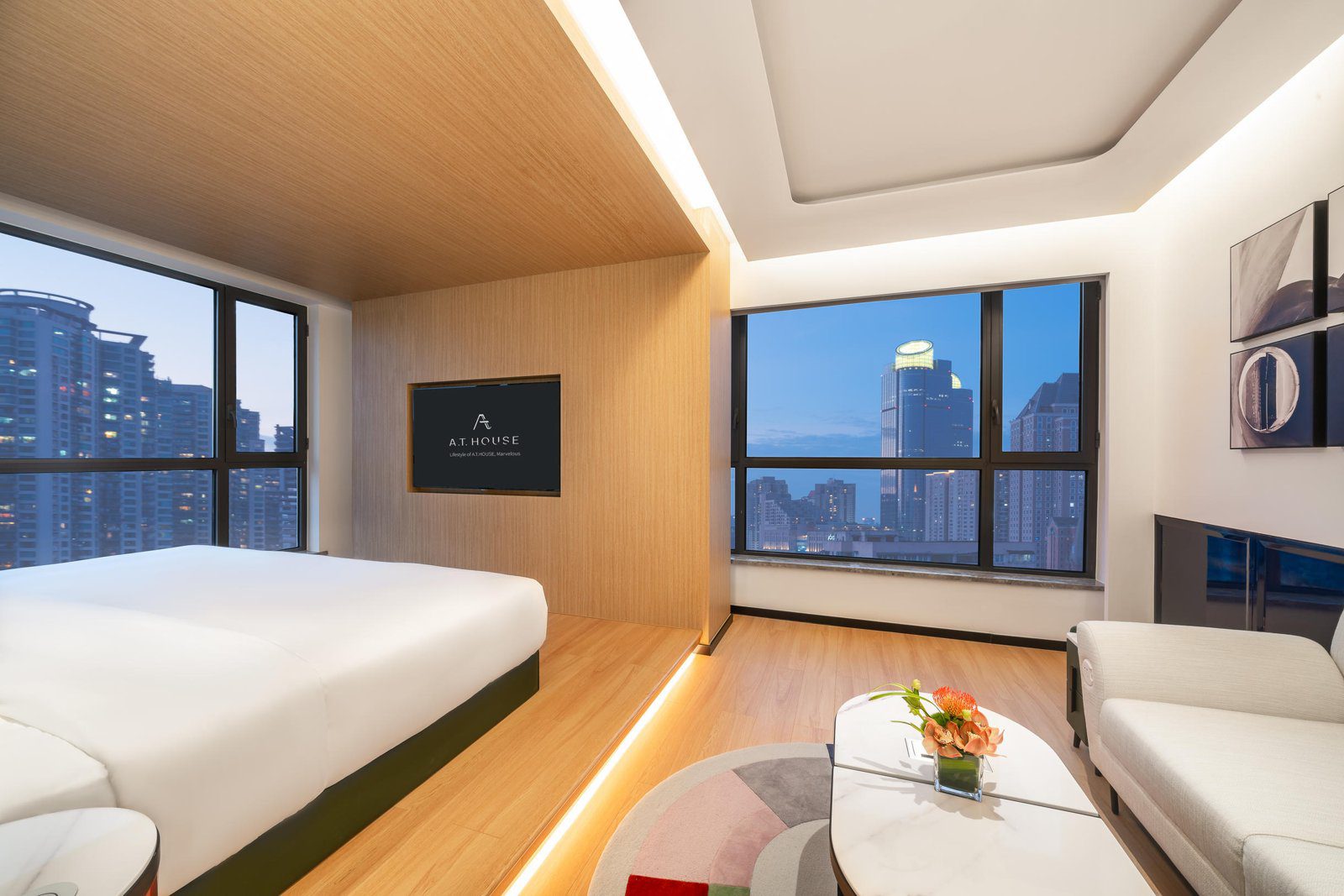 上海徐家匯A.T.HOUSE嘉邸酒店客房內的大床、客廳沙發與轉角窗景
