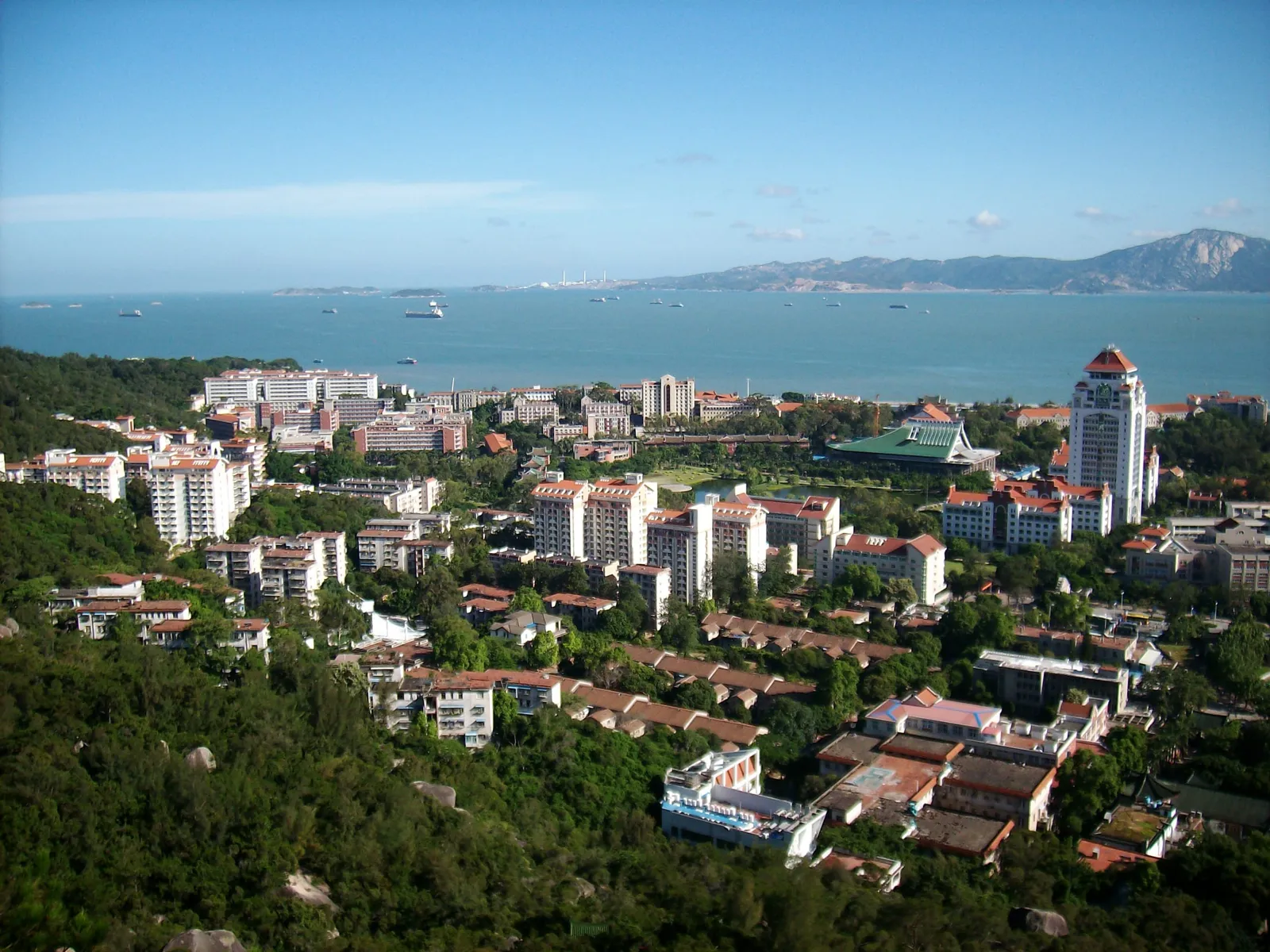 從山上俯瞰濱海的校園建築群與綠樹,遠方是藍色海面